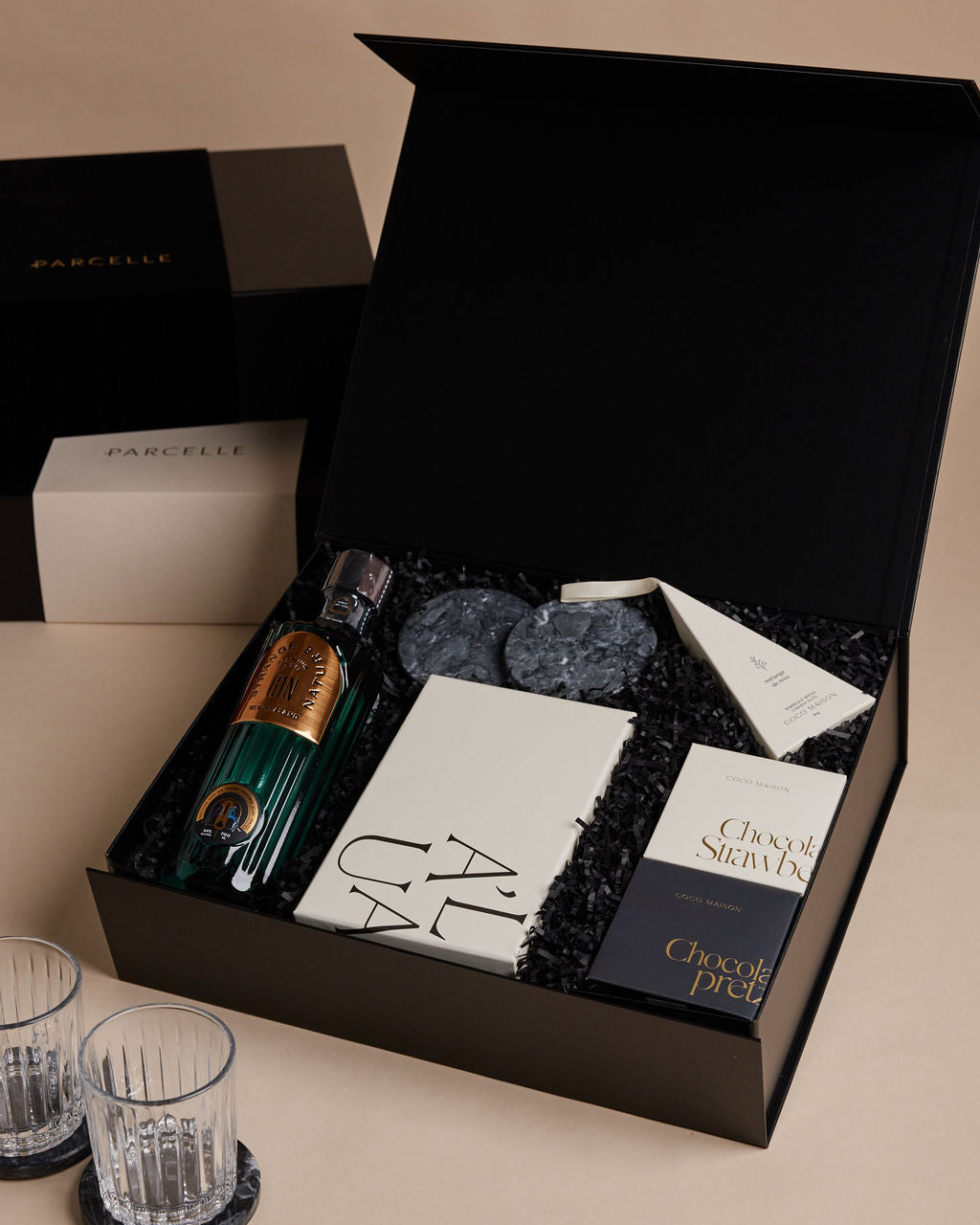 Parcelle | Gourmet gift set with chocolate, wine, and glasses on a beige surface