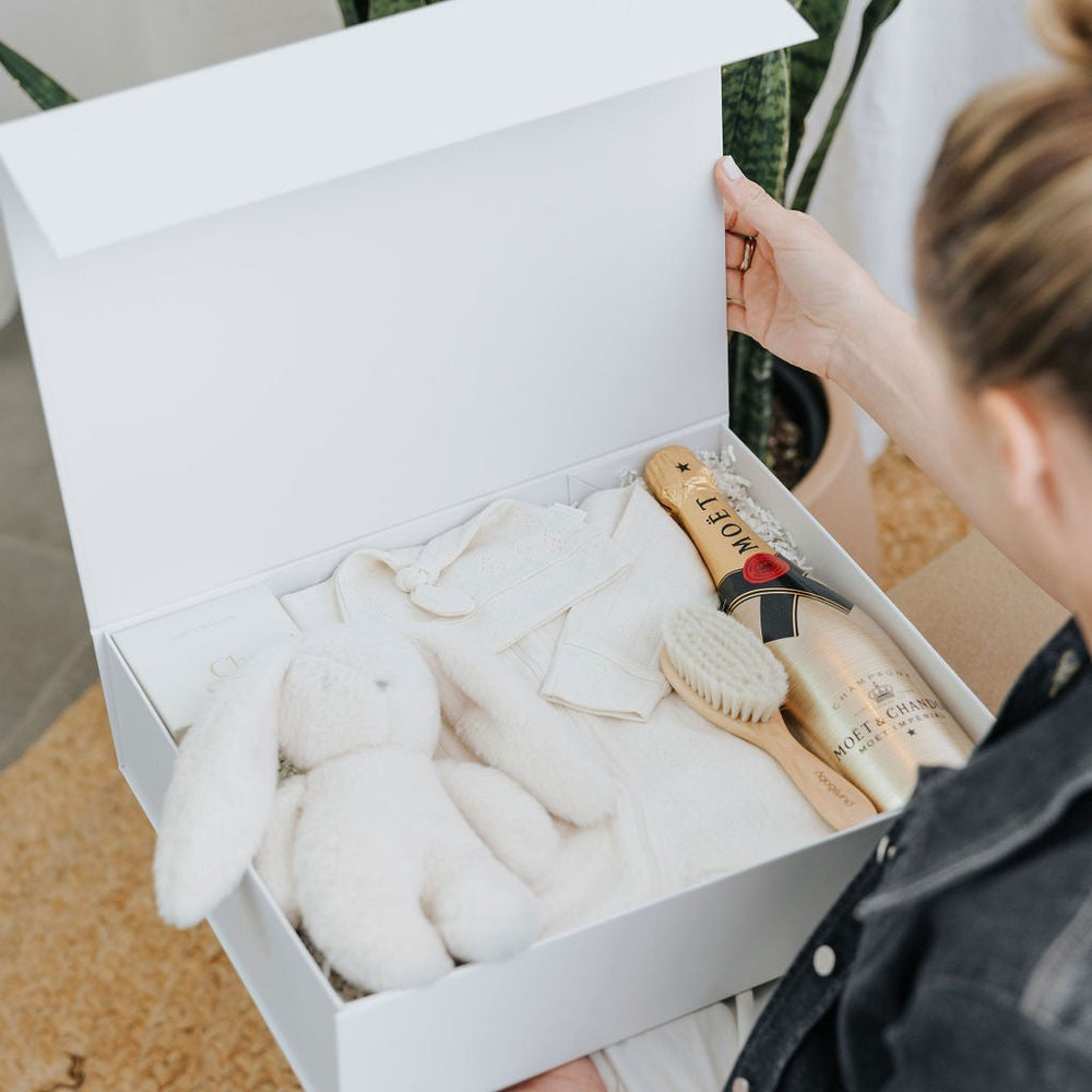 Parcelle | Person unboxing a luxury baby gift hamper from Parcelle, showcasing premium packaging and thoughtful inclusions in a lifestyle setting.
