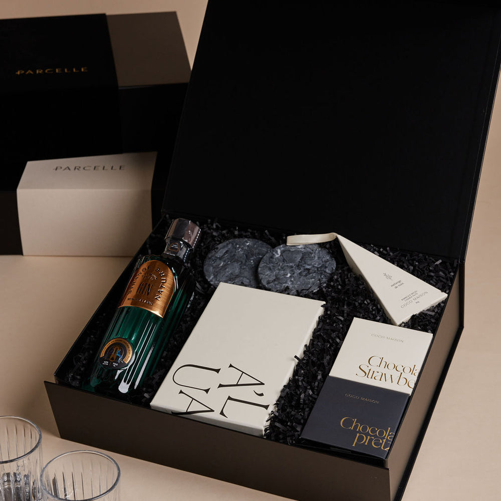 Parcelle | Gourmet gift set with chocolate, wine, and glasses on a beige surface