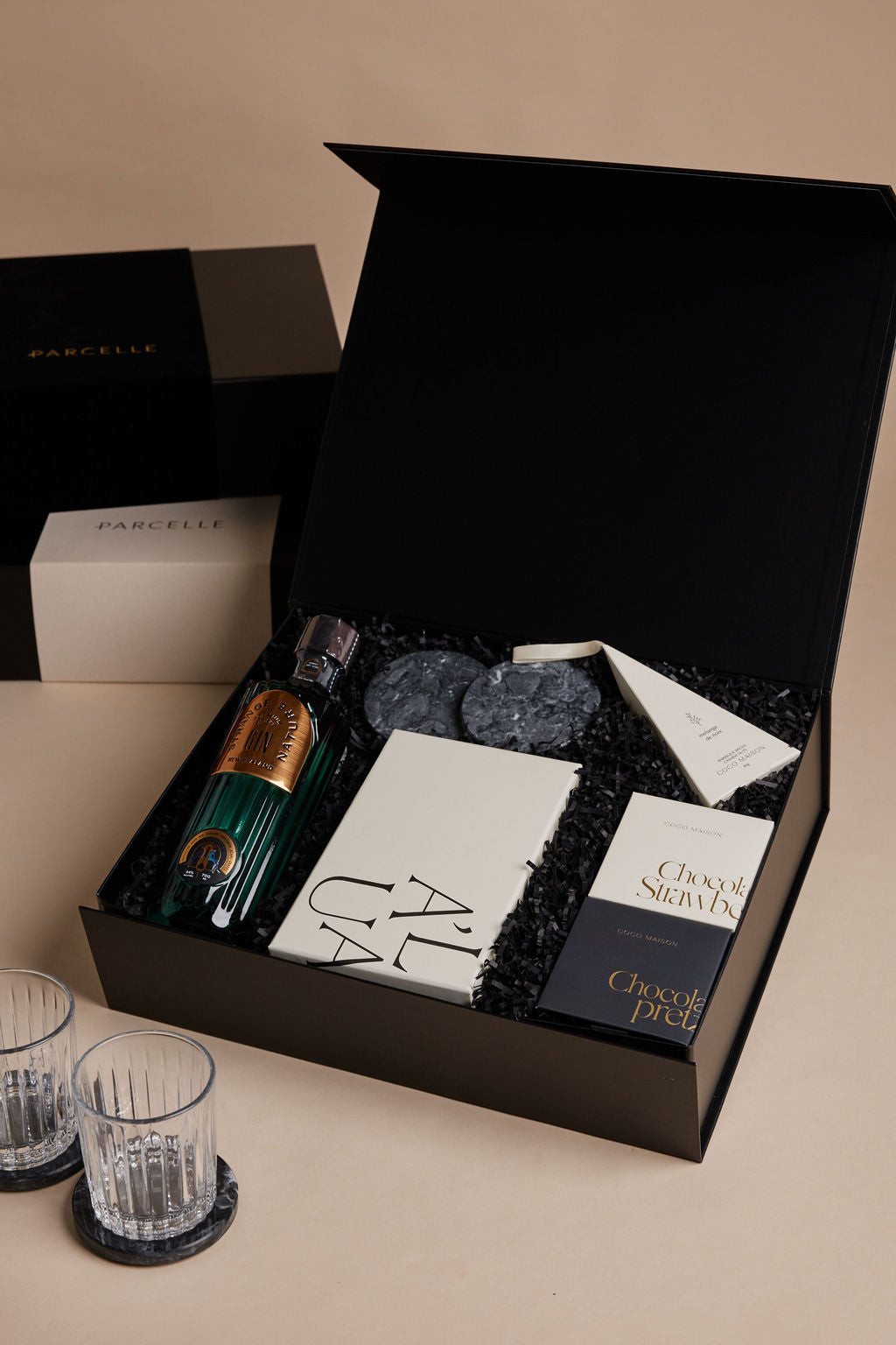 Parcelle | Gourmet gift set with chocolate, wine, and glasses on a beige surface