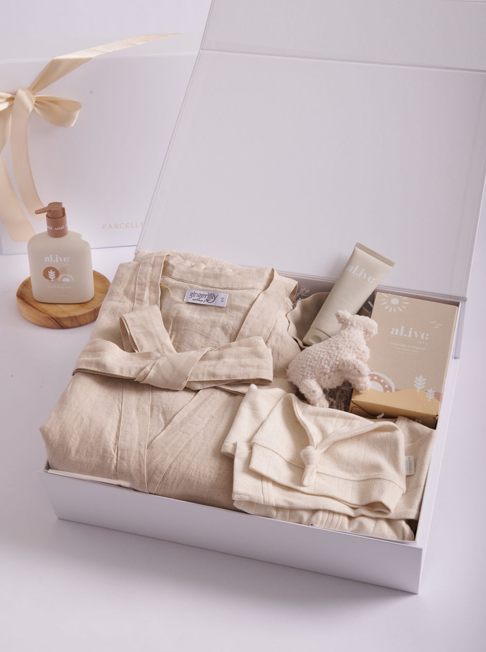 Parcelle | Unltimate New Mum & Baby Gifts | Open Parcelle gift box for baby includes a Purebaby Pointelle Wheat Growsuit and knot hat, alive soothing baby wash, baby lamp rattle, Gingerlilly Linen Robe for mum